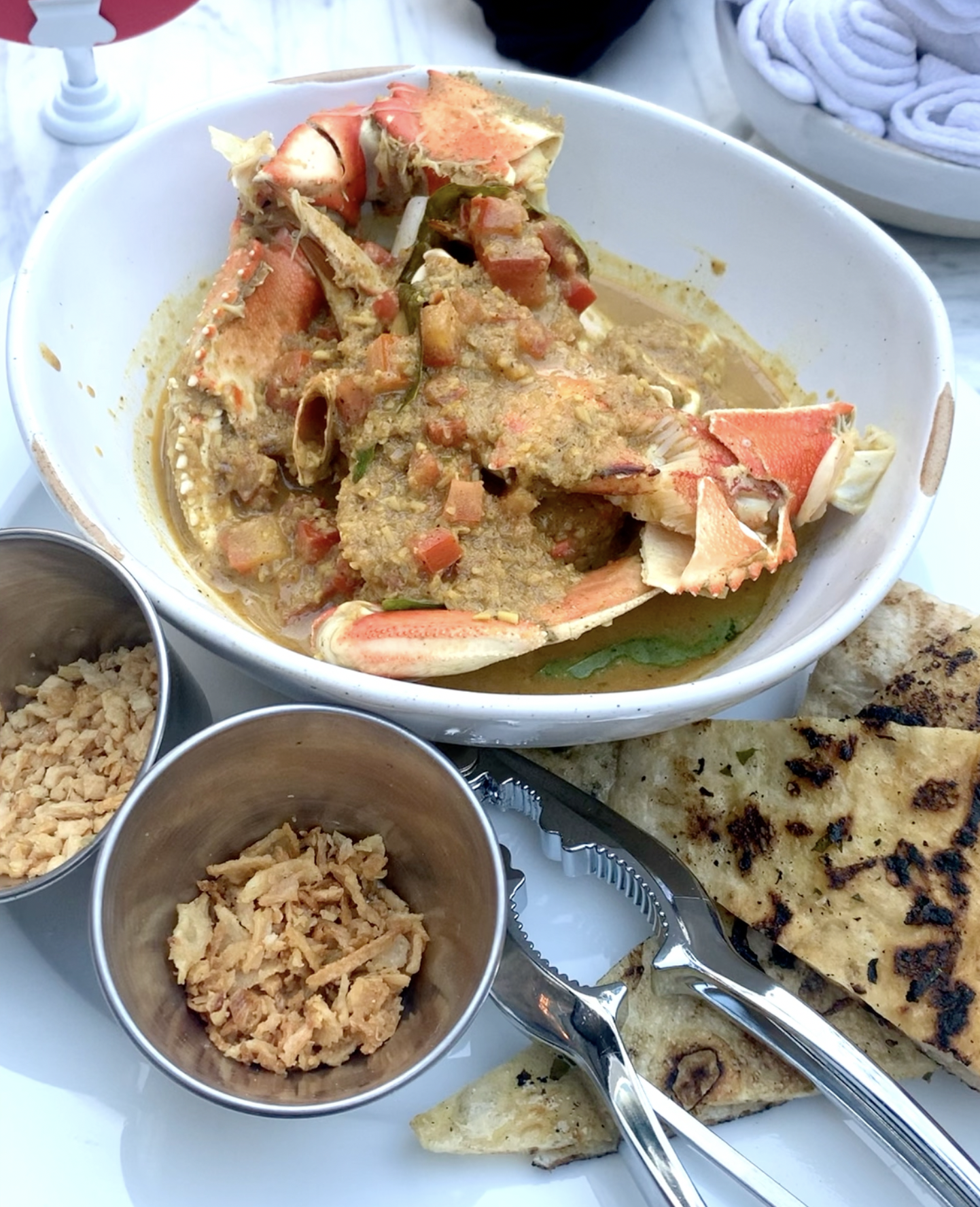 Dungeness crab in a bowl in a curry sauce with pita on the side.