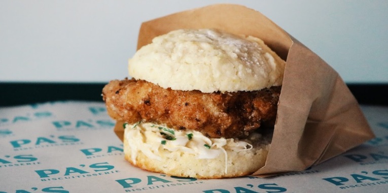 A fried chicken biscuit wrapped in paper.